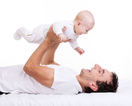 Happy young man holding baby son while lying on back