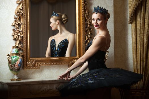 Ballerina in black tutu standing in front of mirror