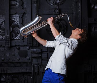 Studio portrait of young cool man with saxophone on black background.
