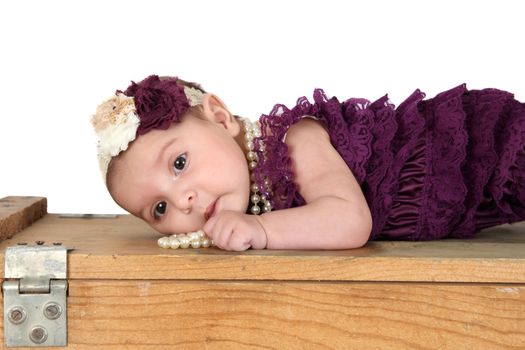 Brunette baby girl wearing a purple romper with pearls