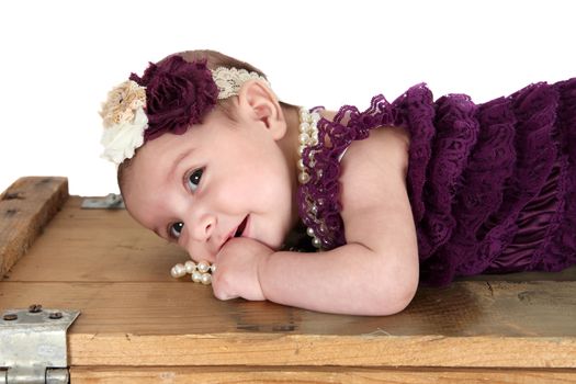 Brunette baby girl wearing a purple romper with pearls