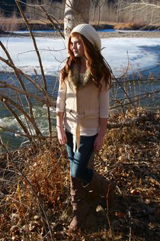 Winter girl leaning against a tree with river in the background