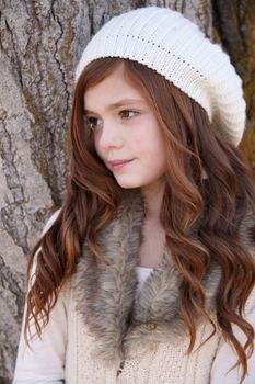 Winter girl standing against a large tree