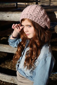 Winter girl leaning against a wooden fence