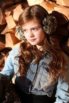 Red haired girl wearing earmuffs against wooden background
