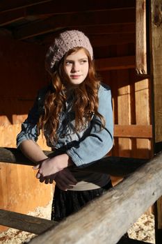 Red haired winter girl standing in barn