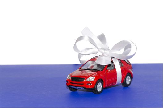 Red car, tied with white ribbon on a blue desktop on a white background