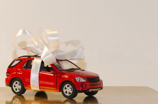 Red car, tied with white ribbon with a Golden table surface