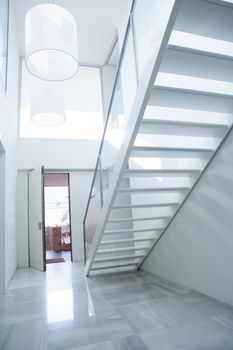 Modern white house entrance hall lobby with stairway and light coming in