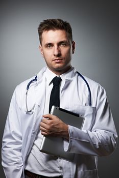 Medical doctor with tablet pc portrait against grey background 