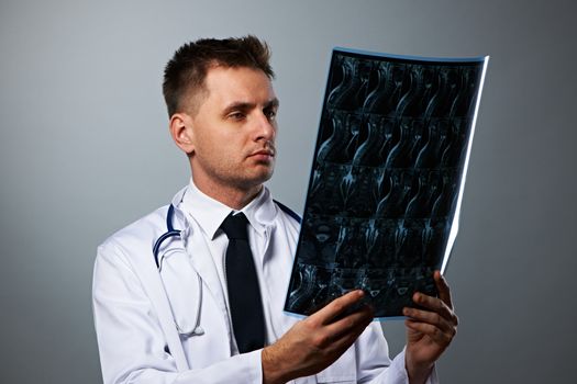 Medical doctor with MRI spinal scan portrait against grey background 