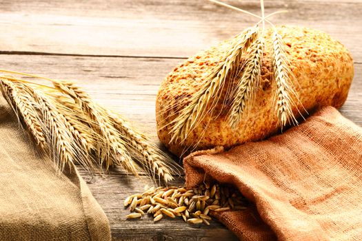 Rye spikelets and bread on wooden background