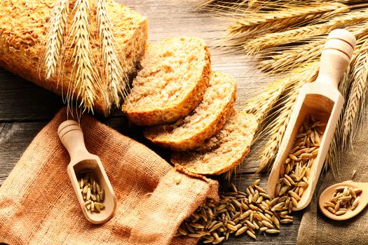 Rye spikelets and bread on wooden background