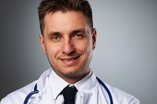 Medical doctor with stethoscope portrait against grey background 