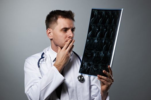 Medical doctor with MRI spinal scan portrait against grey background 