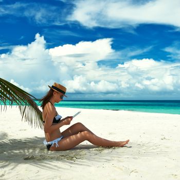 Young woman in hat with tablet pc at the beach