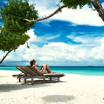 Young woman in hat with tablet pc at the beach