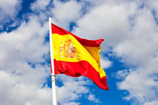 Flag of Spain over blue sky moving in wind