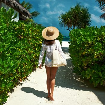 Woman with bag and sun hat going to the beach