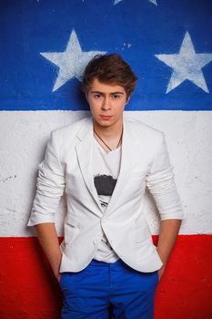Studio portrait of young cool teenager boy on American flag background.