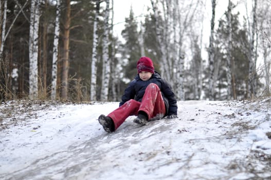 the teenage boy rides from a hill in the snow-covered wood