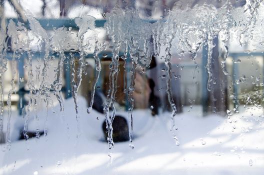 Icicles ice on the glass and the blurred background