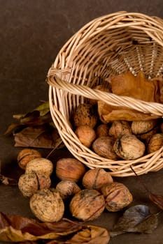Walnuts in wicker basket on brown background
