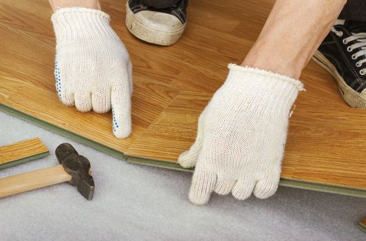 Hands of a master, lay laminate flooring, stylized wood