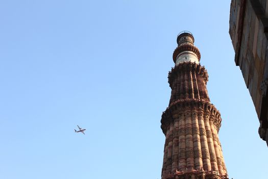 qutub minar with blue sky and plane