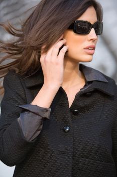 Cheerful woman speaking on mobile phone on street