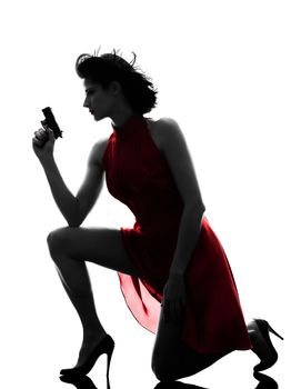 one sexy caucasian woman holding gun in silhouette studio isolated on white background