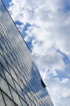 glass surface of a building with reflection of a clouds and sky from above vertically cropped