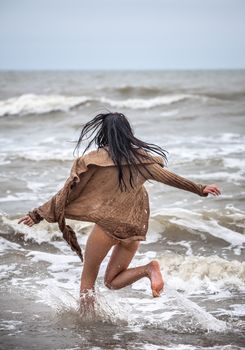 Beautiful young seminude woman in the cold sea waves