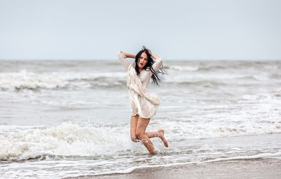 Beautiful young seminude woman in the cold sea waves