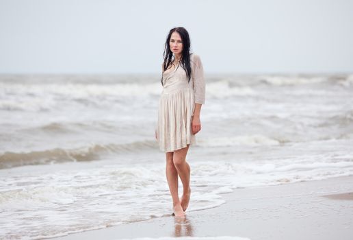 Beautiful young seminude woman in the cold sea waves