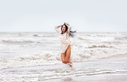 Beautiful young seminude woman in the cold sea waves