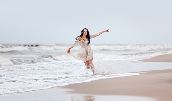 Beautiful young seminude woman in the cold sea waves