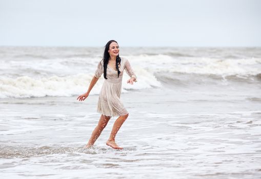 Beautiful young seminude woman in the cold sea waves