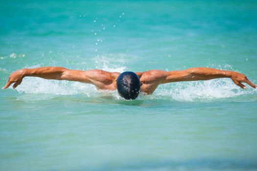 Dynamic and fit swimmer man swimming the butterfly stroke in ocean