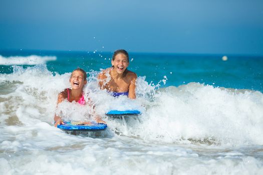 Summer vacation - Two cute girls having fun with surfboard in the ocean