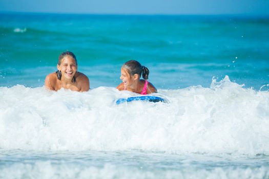 Summer vacation - Two cute girls having fun with surfboard in the ocean