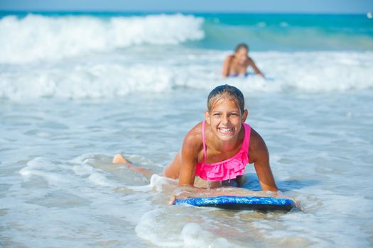 Summer vacation - Happy cute girl having fun with surfboard in the ocean