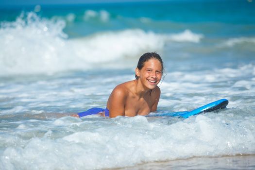 Summer vacation - Happy cute girl having fun with surfboard in the ocean