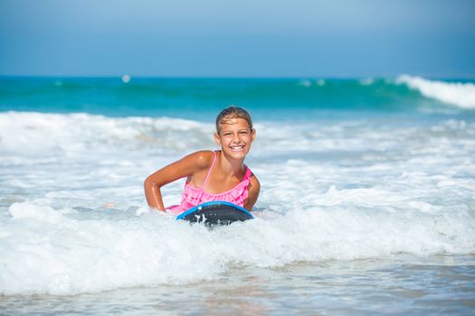 Summer vacation - Happy cute girl having fun with surfboard in the ocean