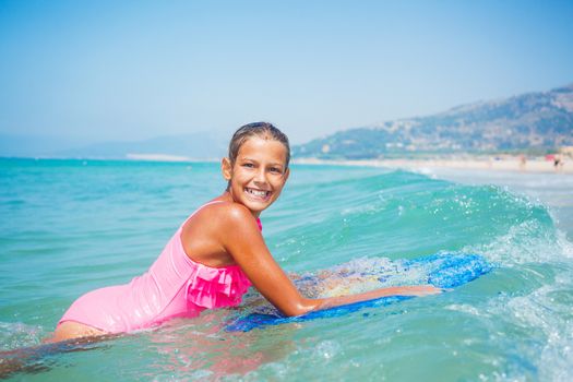 Summer vacation - Happy cute girl having fun with surfboard in the ocean