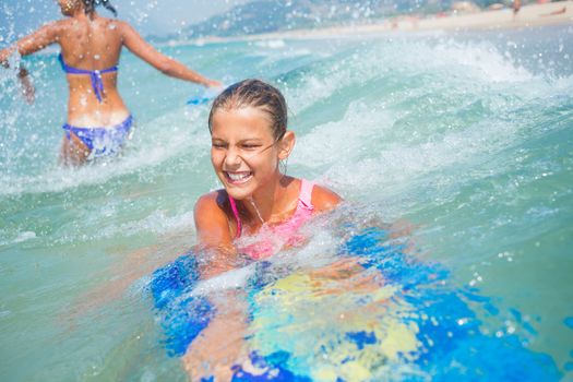 Summer vacation - Happy cute girl having fun with surfboard in the ocean