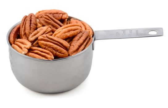 Whole pecan nuts in a metal cup measure, isolated on a white background
