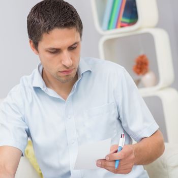 Worried young man paying his bills in the living room at home