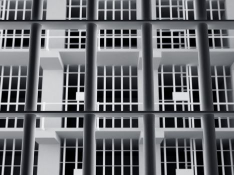 The view from the inside of a brick jail cell with iron bars.