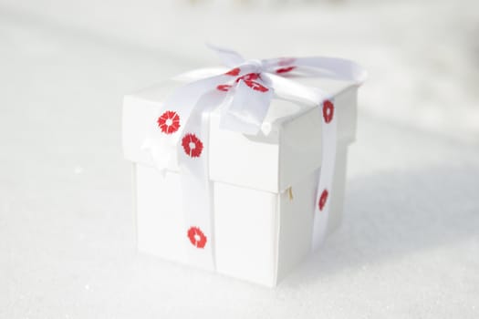 White gift box laying on a snow background.